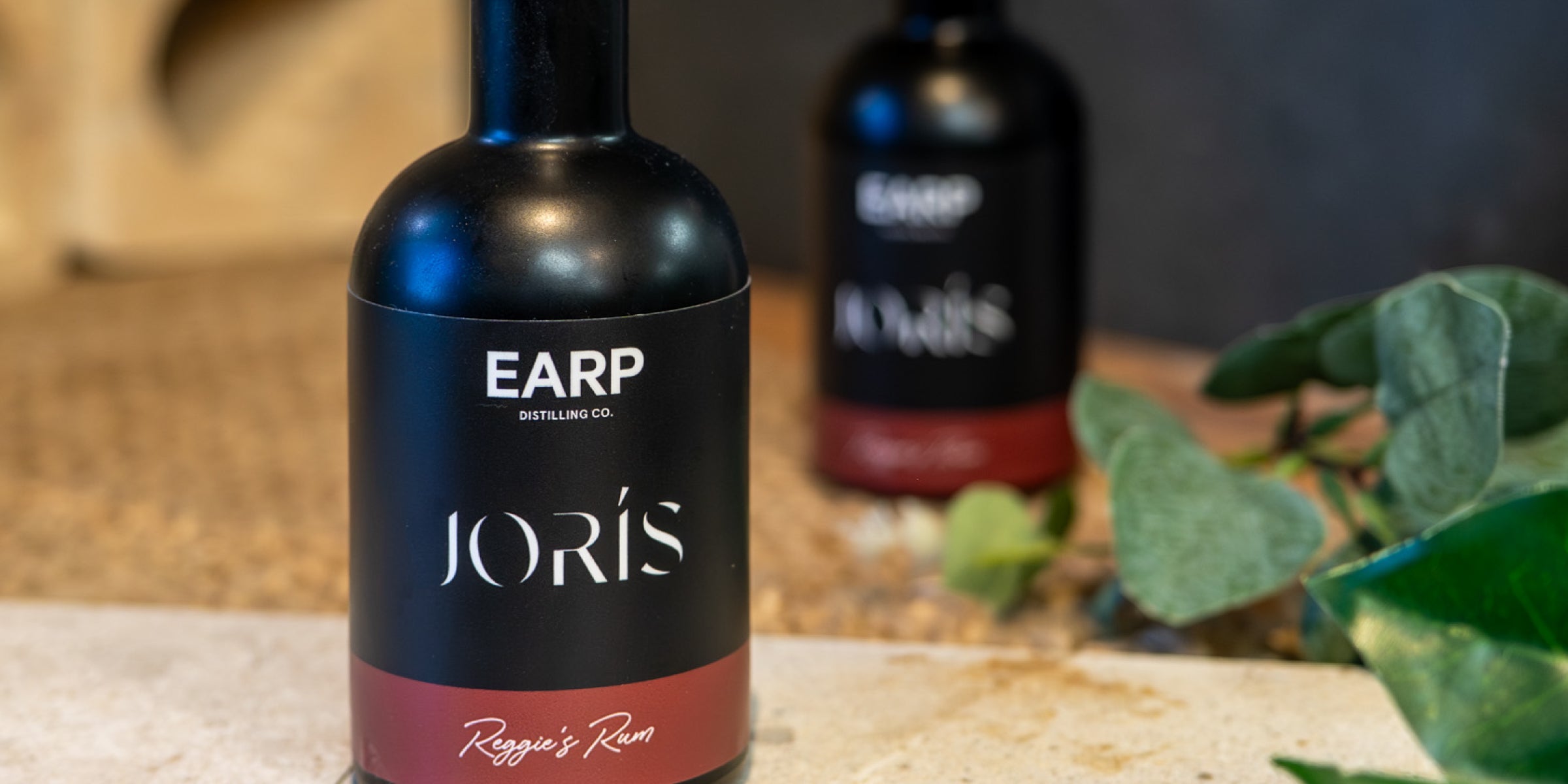 Two 200mL black bottles of rum sit on decorative tiles - branded with Joris Buyers Agents